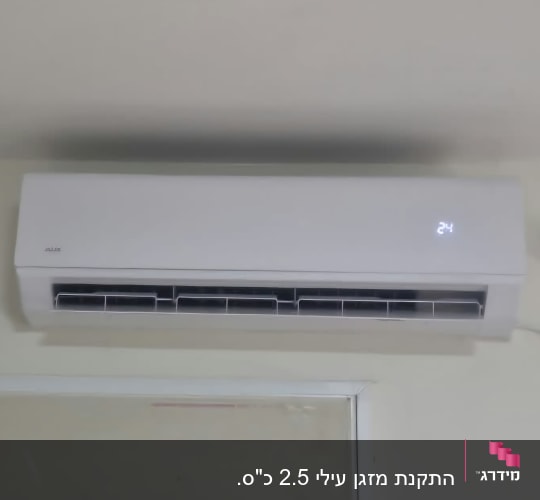 מזגן עילי לבן מותקן ועובד על קיר בבית